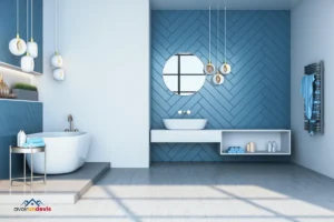 Salle de bain moderne avec un mur bleu en chevrons, une baignoire blanche sur une plateforme, un lavabo blanc sur un meuble suspendu, et des luminaires suspendus élégants.
